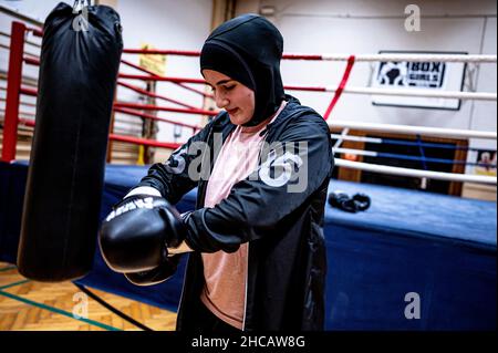 Berlin, Deutschland. 16th Dez 2021. Boxtrainerin Doha Taha Beydoun trainiert mit einer ihrer Boxer. Sie ist erst 20 Jahre alt. Verheiratet. Vier Monate schwanger. Muslim und ein Boxtrainer. Ihre Eltern emigrierten als Baby aus dem Libanon nach Deutschland. Doha Taha Beydoun scheint einigen „trange“ zu sein, sagt sie, weil ihre Nationalität, Religion und ihr Sport nicht übereinstimmen. Andere sehen sie als Vorbild, wie sie selbst sagt. "Ich Kämpfe gegen alle Vorurteile", sagt die junge Frau zuversichtlich. Quelle: Fabian Sommer/dpa/Alamy Live News Stockfoto