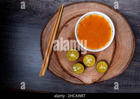 Gemahlene Chilisauce und Limettenscheiben auf einem hölzernen Schneidebrett. In der Regel für zusätzliche Würze für Fleischbällchen, Nudeln, Vermicelli usw. Stockfoto