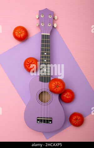 Viersaitige Ukulelegitarre mit Mandarinen auf farbigem Hintergrund, Draufsicht. Stockfoto