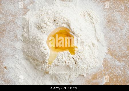 Flatlay von Haufen gesiebenem Mehl mit rohem Ei auf der Oberseite bereit für die Vorbereitung von hausgemachtem Teig und Gebäck Stockfoto