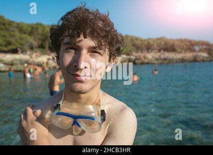 Porträt eines niedlichen kaukasischen jungen Mannes, der an der Bucht von Porto Selvaggio, Apulien, Italien, steht. Erzählen Sie uns von seiner Erfahrung an diesem großartigen Ort. Stockfoto