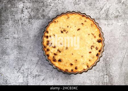 Quark-Auflauf mit getrockneten Preiselbeeren in einer Glasauflaufform auf dunkelgrauem Hintergrund. Draufsicht, flach liegend Stockfoto