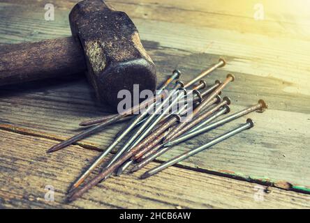 Alter Hammer und Nägel auf einer Holzbank Stockfoto