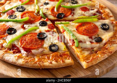 Traditionelle, erstklassige Pizza auf einem rustikalen Holztisch Stockfoto