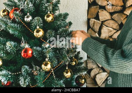 A woman decorates a Christmas tree at home. The concept of celebrating and preparing for Christmas and New Year Stockfoto