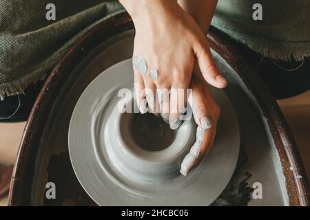 Eine Handwerkerin arbeitet in einer Tonwerkstatt auf einem Töpferrad. Das Konzept kreativer Menschen. Stockfoto