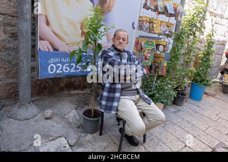 Ein arabischer Ladenbesitzer im Christlichen Quater der Altstadt von Jerusalem sitzt ruhig vor seinem Laden. Stockfoto