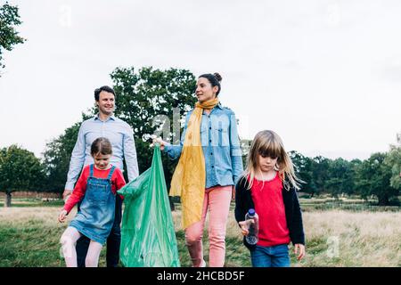 Familie mit Müllsack läuft im Park Stockfoto