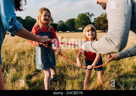 Töchter und Eltern halten Hula Hoop, während sie im Park spielen Stockfoto