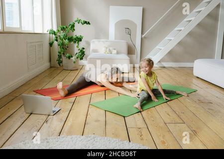 Mutter unterrichtet der Tochter Yoga auf der Übungsmatte Stockfoto