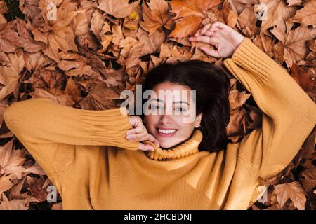 Junge Frau, die auf Ahornblättern ruht Stockfoto