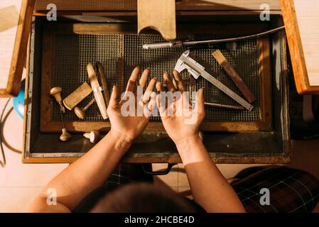 Verkürzte Hand einer Juwelierin mit herzförmiges Schmuckstück in der Werkstatt Stockfoto