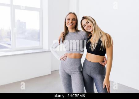 Porträt von zwei fittern Frauen, die in einem hellen Fitnessraum lächeln Stockfoto