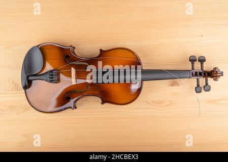Draufsicht auf die Geige und die darauf liegende Saite. Holzhintergrund. Speicherplatz kopieren. Stockfoto