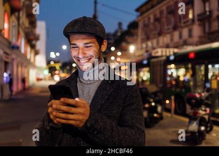 Glücklicher junger Mann mit Smartphone in der Stadt Stockfoto