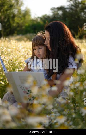 Mutter und Tochter lesen auf der Wiese das Märchenbuch Stockfoto