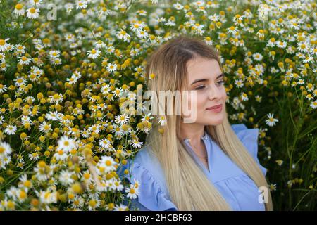 Blonde Frau, die inmitten von Blumen auf der Wiese nachdenkt Stockfoto