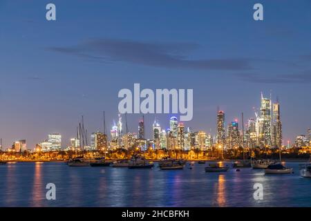 Australien, Victoria, Melbourne, Yachten, die in der Abenddämmerung gegen die beleuchtete Skyline der Stadt schweben Stockfoto