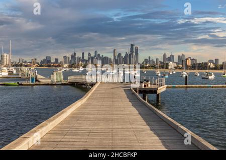 Australien, Victoria, Melbourne, Yachten, die in der Abenddämmerung gegen die beleuchtete Skyline der Stadt schweben Stockfoto