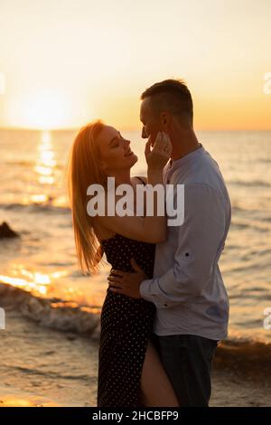 Romantisches junges Paar, das den Sonnenuntergang am Strand genießt Stockfoto