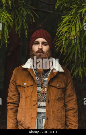 Junger bärtiger Mann mit Jacke im Wald Stockfoto