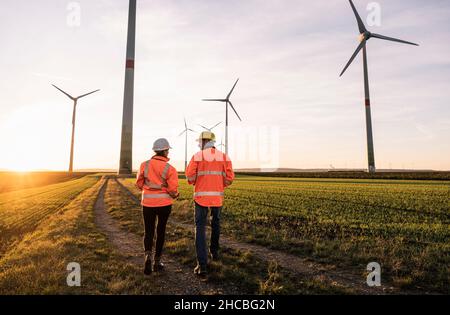 Ingenieure in reflektierender Kleidung laufen im Windpark Stockfoto