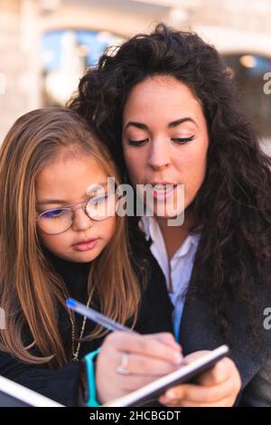 Lächelnde Tochter mit Buch von Mutter Stockfoto