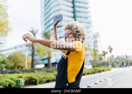 Frau mit Mobiltelefon und Tanz auf der Straße Stockfoto