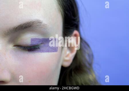 Frau mit geschlossenen Augen und Make-up vor Lavendel Hintergrund Stockfoto