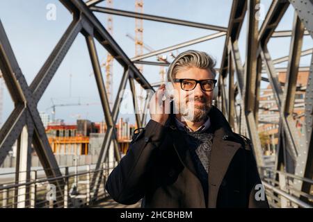 Lächelnder bärtiger Geschäftsmann auf der Brücke Stockfoto