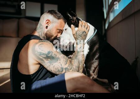 Mann, der zu Hause von Angesicht zu Angesicht mit Hund sitzt Stockfoto