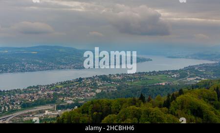 Panorama-Luftaufnahme des Zürichsees und der zürcher Stadtlandschaft an einem bewölkten Sommertag, vom Uetliberg in Zürich aus gesehen. Stockfoto