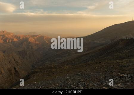 Schöner Blick auf die Hajar-Bergkette vom Gipfel des Jebel jais bei Sonnenuntergang in Ras Al Khaimah, Vereinigte Arabische Emirate. Karges Landschaftskonzept. Stockfoto