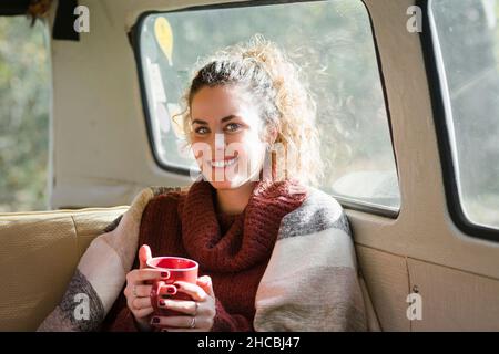 Schöne Frau mit Kaffee im Wohnmobil Stockfoto