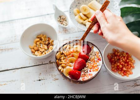 Frau mit Löffel mit frischem Fruchtjoghurt am Tisch Stockfoto