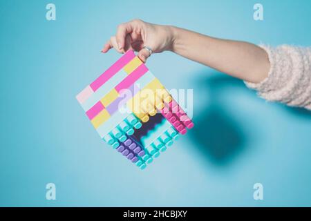 Arm einer Frau mit einem bunten Würfel aus pastellfarbenen Spielzeugblöcken Stockfoto