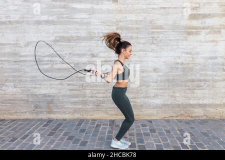 Sportlerin mit Seilspringen an der Wand Stockfoto