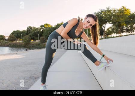 Lächelnder Athlet berührt die Zehen auf den Stufen im Park Stockfoto