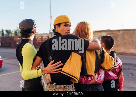 Mann mit Arm um Freunde auf der Straße Stockfoto