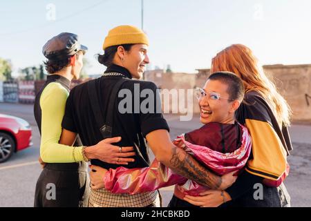 Glückliche Frau mit Arm um Freunde auf der Straße Stockfoto