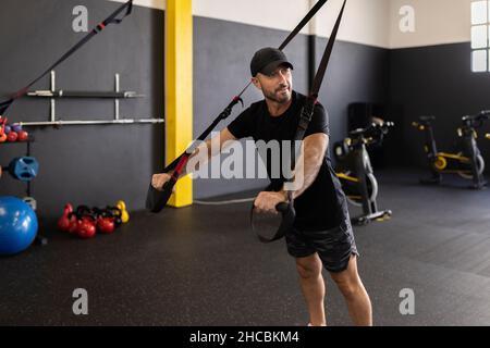 Trainer mit Gurten, der Athleten im Fitnessstudio anweist Stockfoto