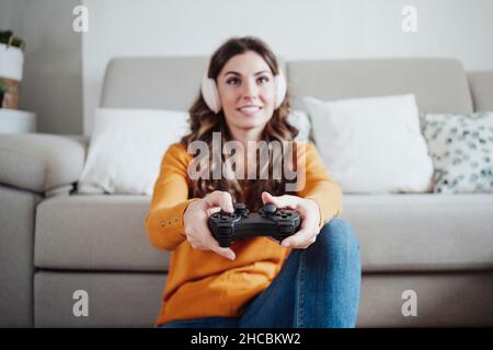 Junge Frau mit Kopfhörern, die zu Hause Videospiele spielt Stockfoto