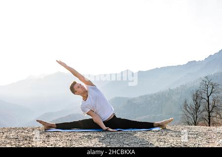 Mann, der Yoga mit Blick auf die Berge praktiziert Stockfoto