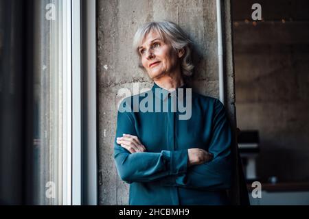 Durchdachte Geschäftsfrau mit Kaffeetasse, die in der Cafeteria sitzt Stockfoto