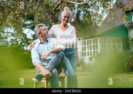 Nachdenkliche Frau, die sich auf den Mann im Hinterhof stützt Stockfoto