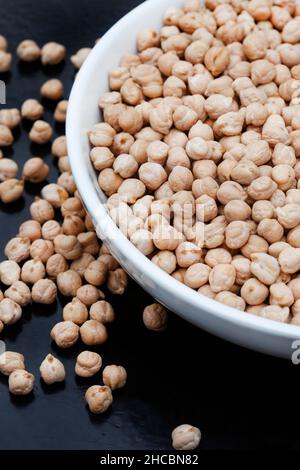 Schüssel mit rohen, ungekochten Kichererbsen auf rustikaler Oberfläche Stockfoto