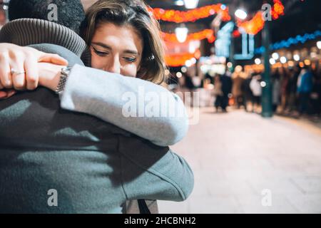 Paare umarmen sich gegenseitig auf dem beleuchteten Weihnachtsmarkt Stockfoto