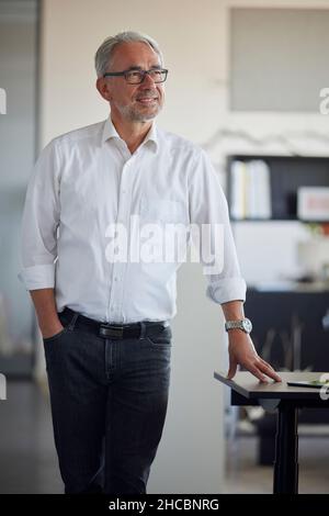 Lächelnder Geschäftsmann mit Brillen im Büro Stockfoto