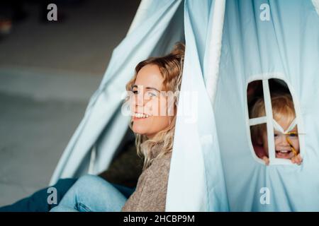 Die Eltern schauten sich im Wohnzimmer eine fröhliche Tochter auf dem Schoß an Stockfoto