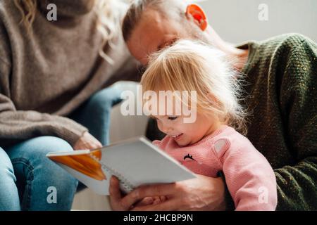 Mann umarmt Frau sitzt mit Mädchen vor dem Zelt zu Hause Stockfoto